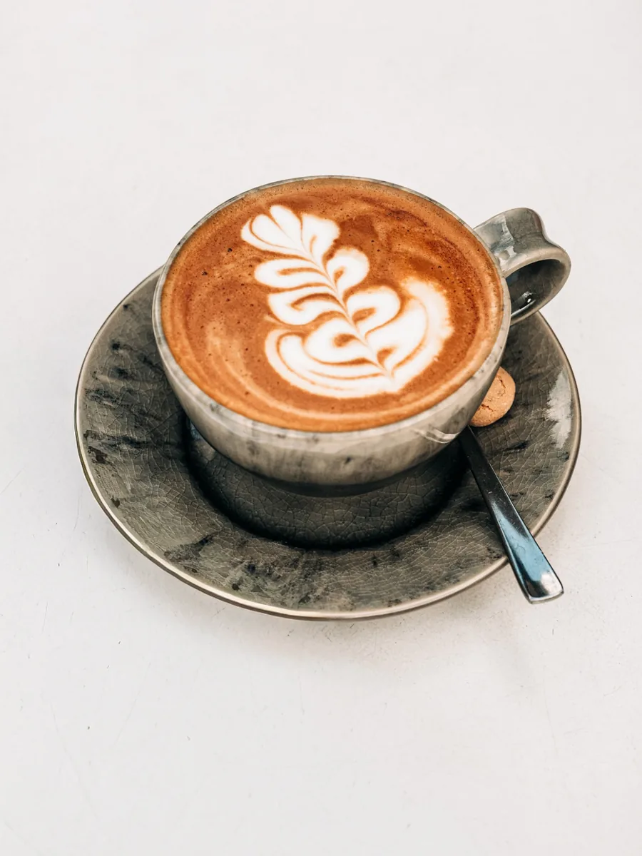 Cappuccino mit Latte-Art in einer handgetöpferten Tasse